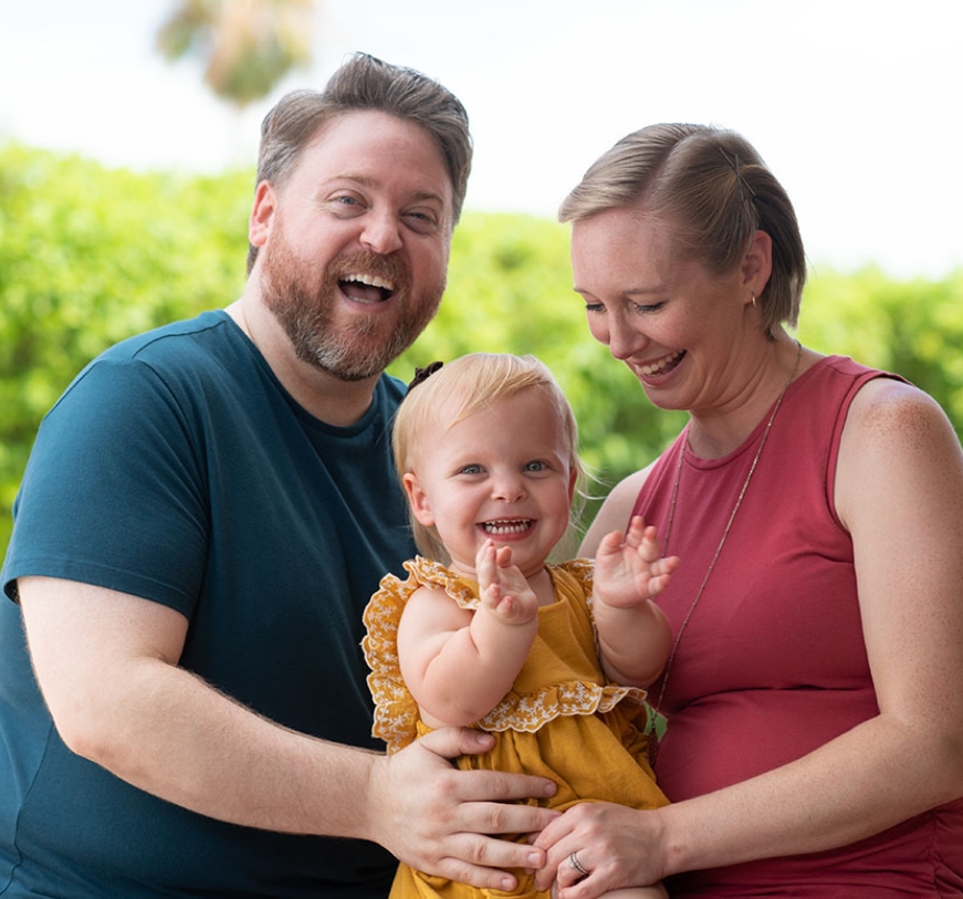 Smiling family portrait with mother, father, and a young child with achondroplasia